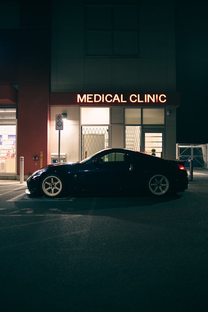 Low-angle side view of a Nissan 350Z parked outside a medical clinic at night.